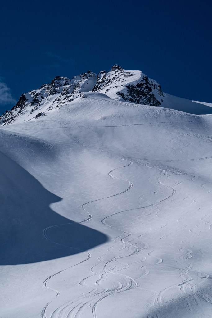 skiing winter powder with the jagged peak of Phalanx Mountain standing in the background