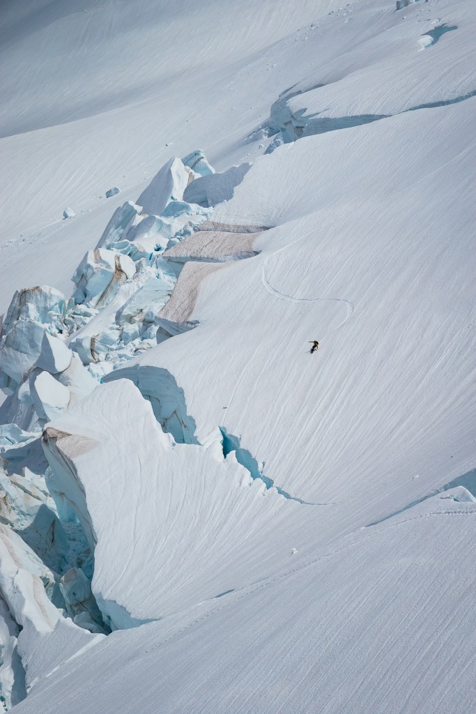Tomoki Fuse riding down by a massive ice fall on Coleman glacier at Mount Baker