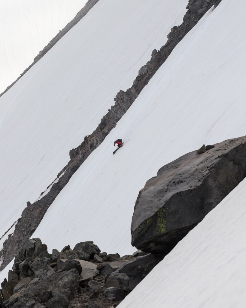 Kenji Kono making dynamic ski turns down the rider right face of Inter Glacier on a cloudy day