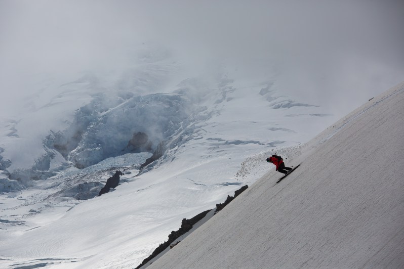 Kenji Kono making dynamic ski turns down the rider right face of Inter Glacier on a cloudy day